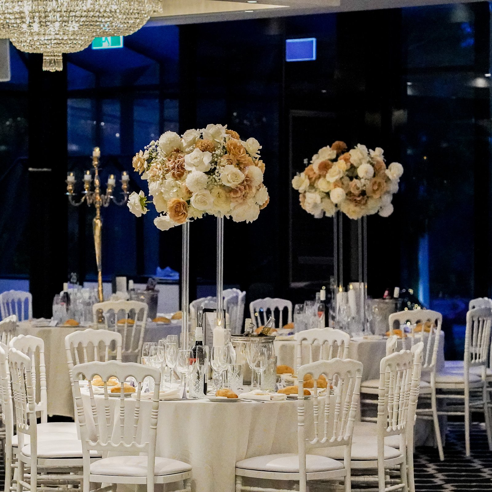 White and toffee-themed wedding reception centerpiece with elegant floral arrangements and candles, creating a sophisticated and timeless ambiance