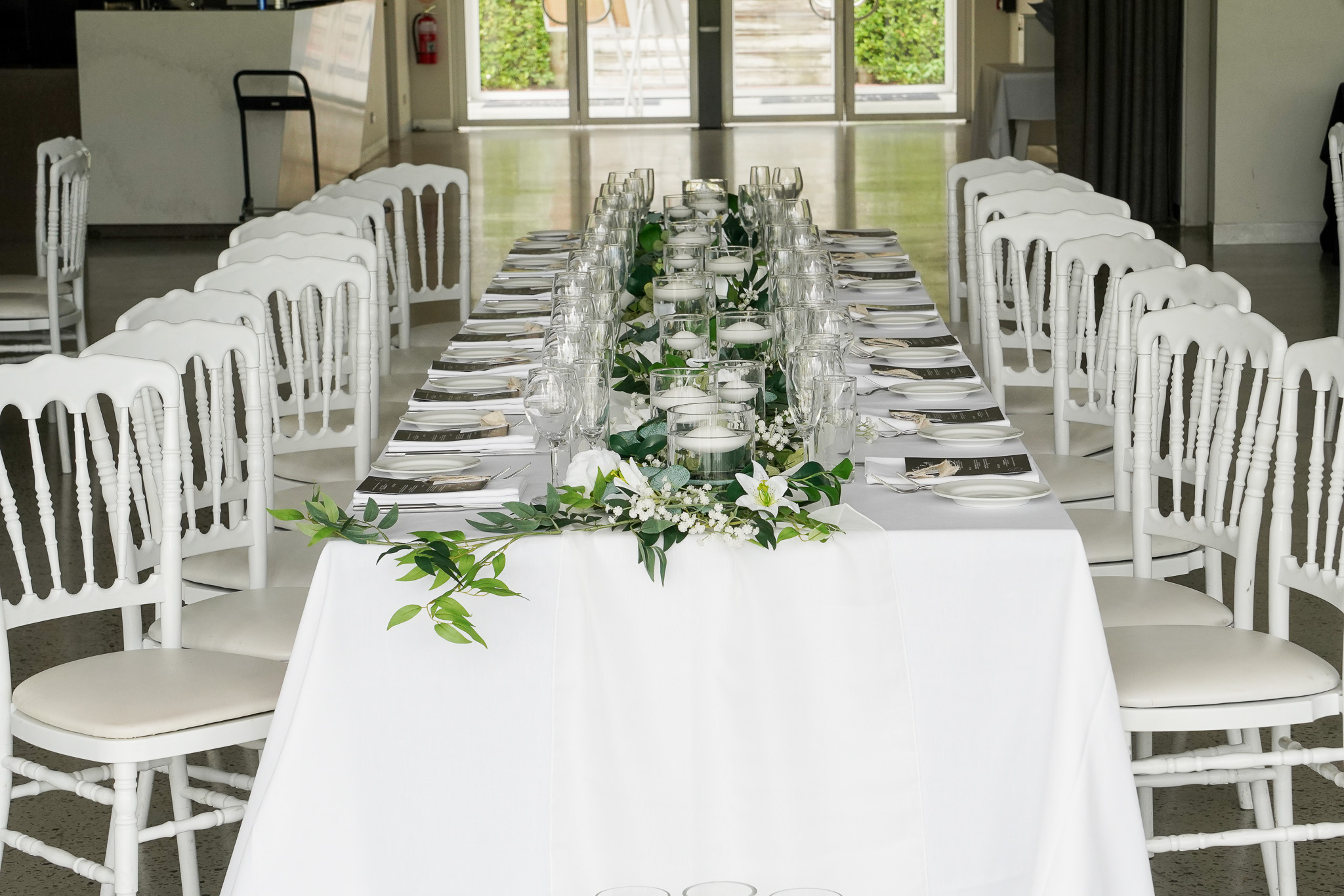 Silk flower decorated wedding reception table with greenery runner, white roses, and baby's breath